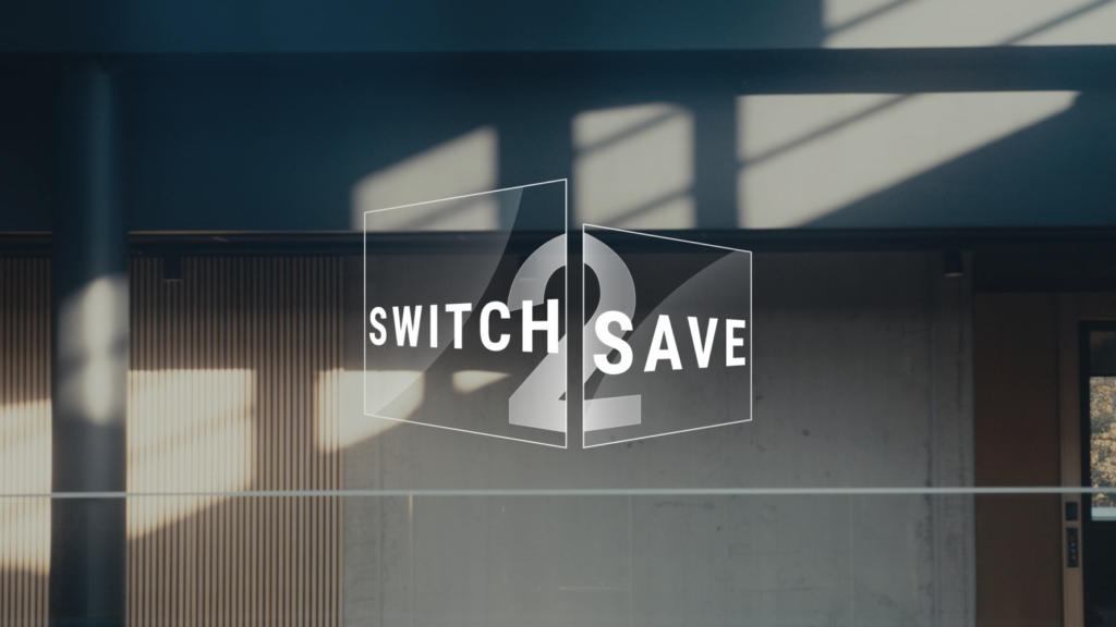 The text "Switch2Save" in white against a background of a modern building interior with concrete walls and shadow play.