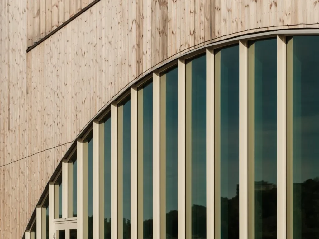 Close-up of wood-clad building with rounded windows and vertical panels
