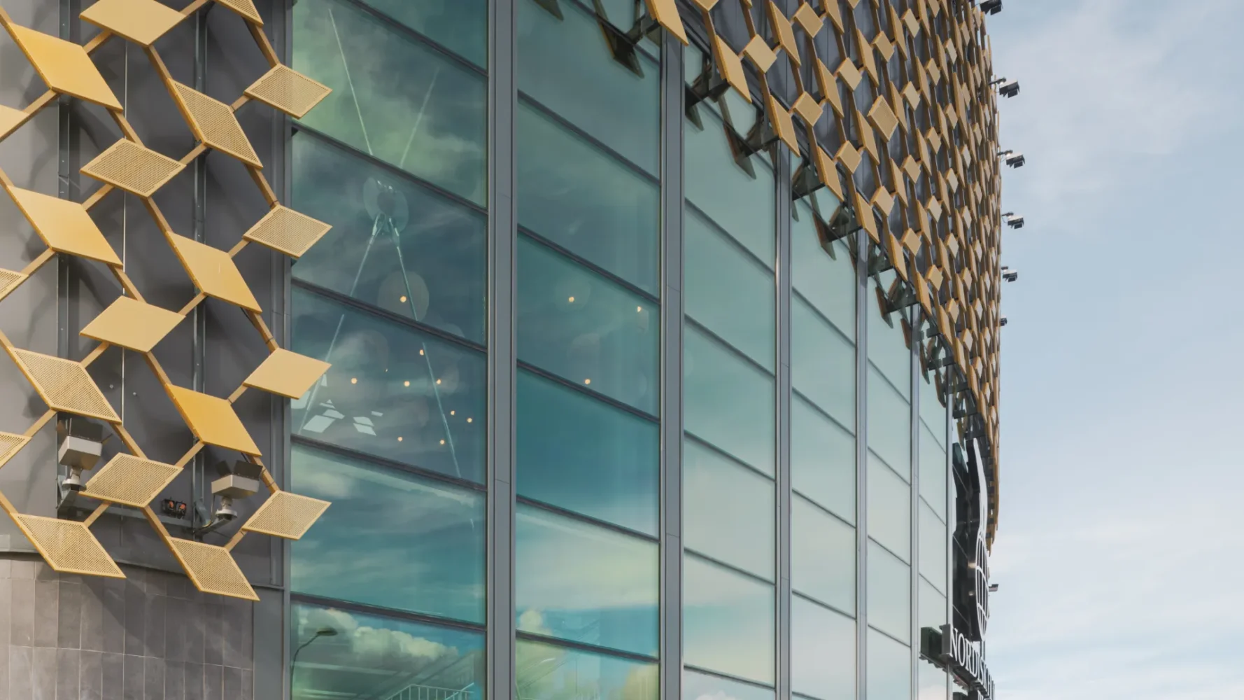 Curved glass facade on a building with gold-colored facade elements.