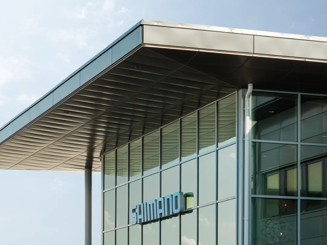 Eingangsfassade mit großen Fenstern, blaues Shimano-Logo.