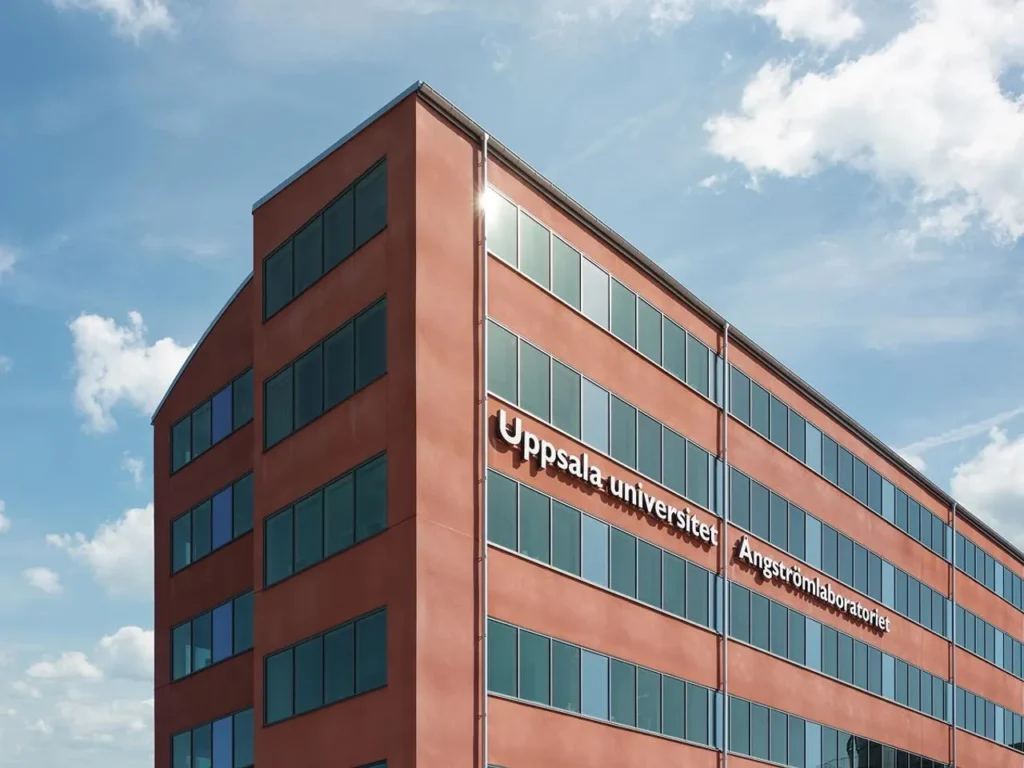 Red building with large glass sections and the text 'Uppsala University Ångström Laboratory' on the facade.