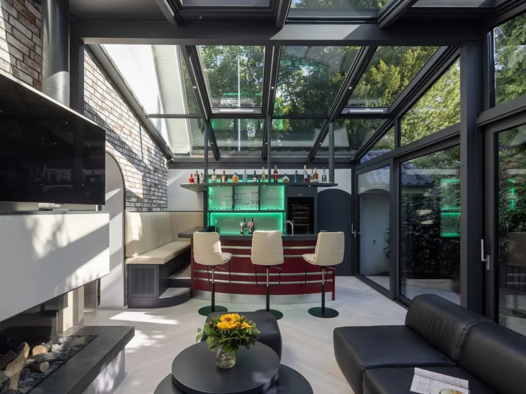 Glass pavilion in a garden setting with a black frame and open glass sections that let in daylight.