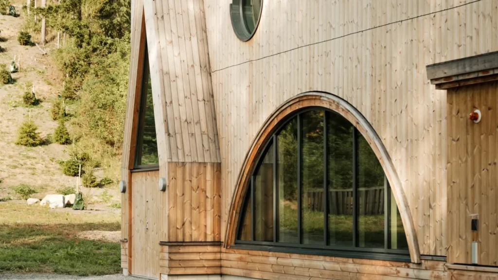 Close-up of wood-clad building with rounded windows and vertical panels